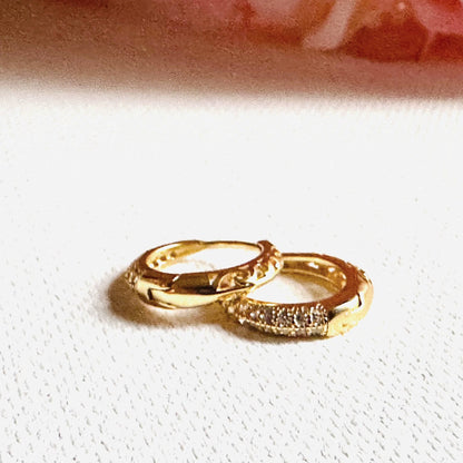 Gold huggie hoop earrings with crystal accents and polished finish. Ideal for elevating any outfit with a touch of shine.