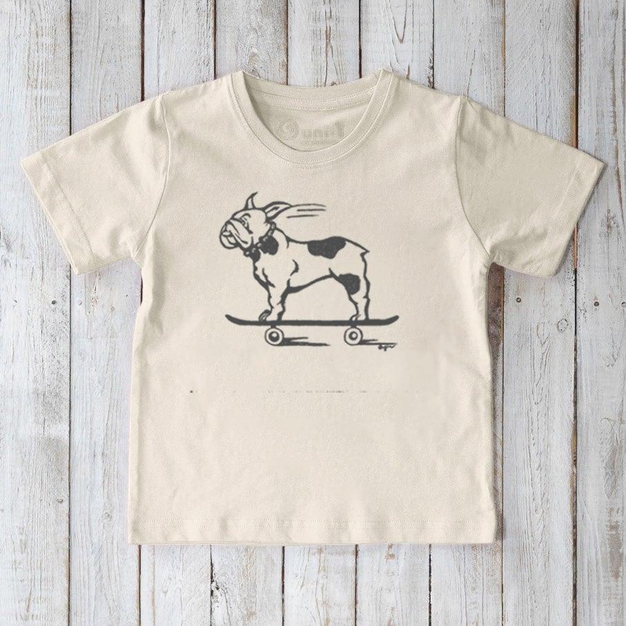 Cream-colored Kids’ Organic Cotton T-Shirt with a black French Bulldog on skateboard print. Sustainable Uni-T graphic top for children.