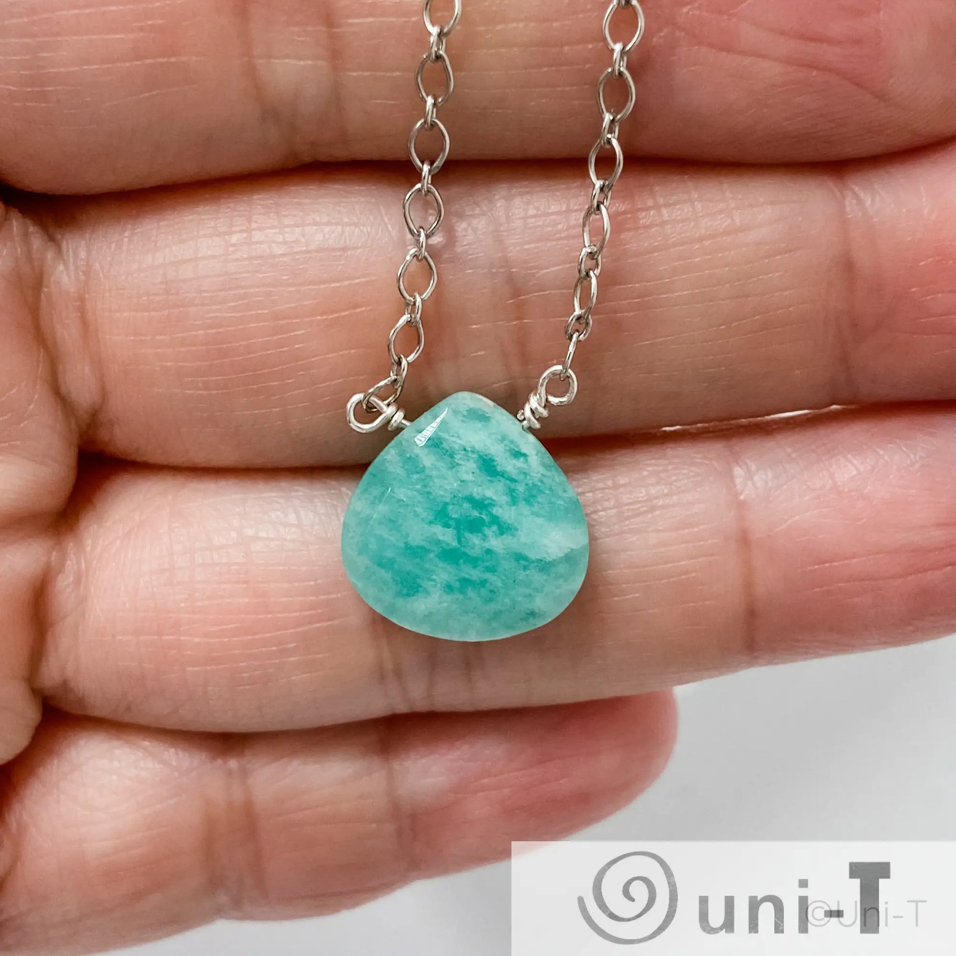 Close-up of Uni-T Amazonite Gemstone Necklace with hand-cut green-blue stone on silver chain, highlighting pendant size and detail.