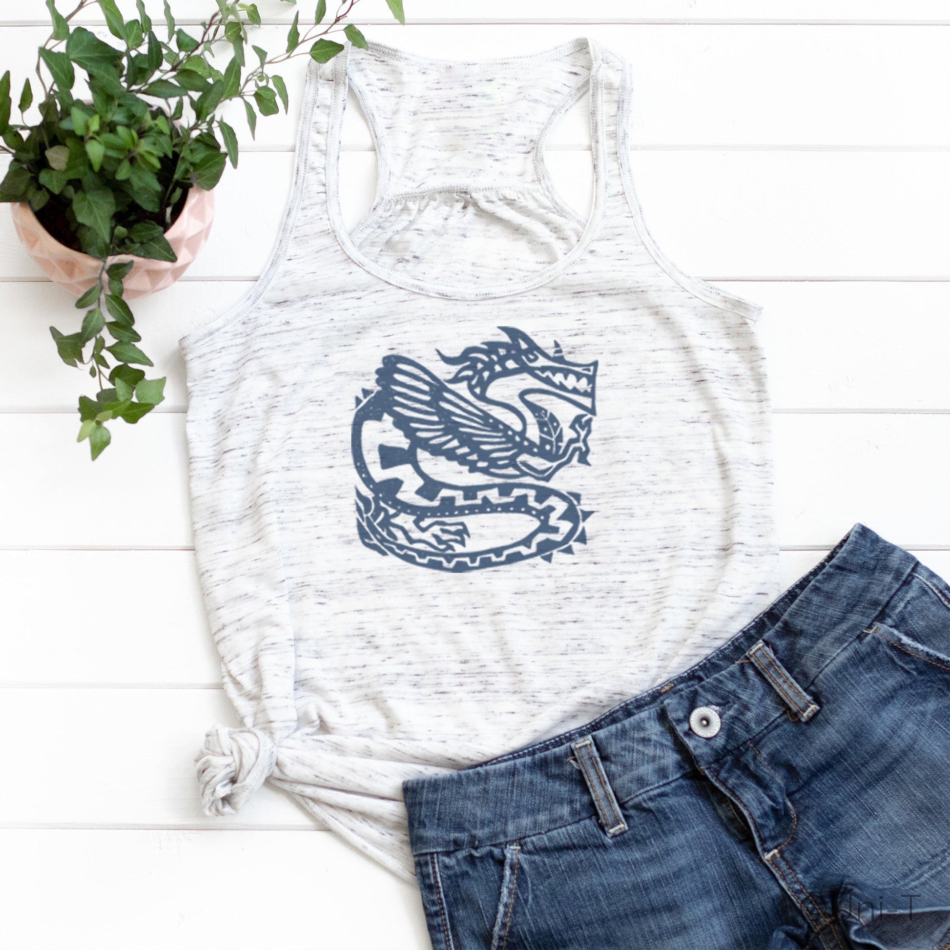 White racerback dragon tank top for women featuring a bold mythical dragon design, styled with denim shorts for a casual look.