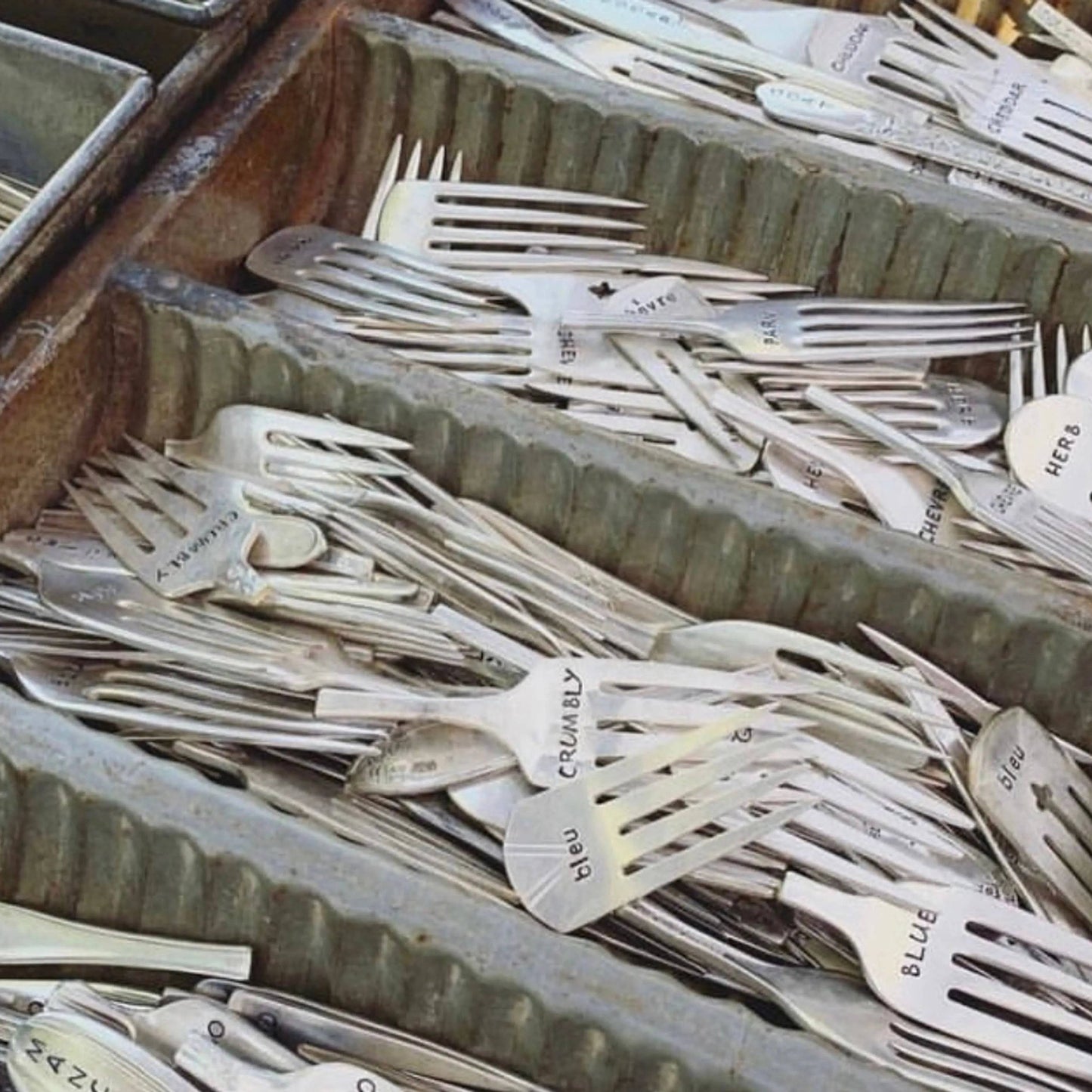 Cheese markers made from repurposed silver forks labeled with cheese names like JACK, displayed in a vintage metal tray. Ideal for cheese boards.