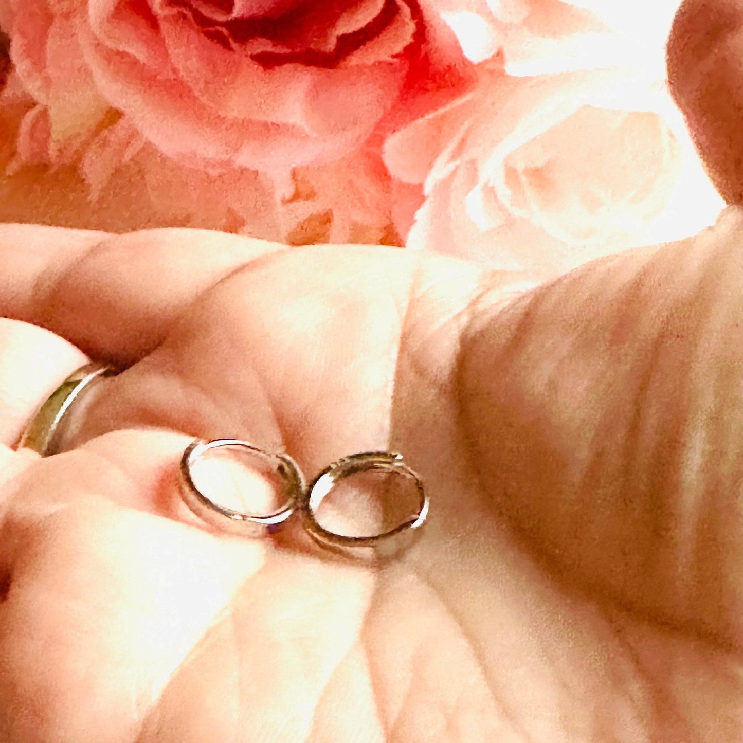 Small silver huggie hoop earrings displayed in hand, showcasing their compact size and polished finish. Ideal for minimalist style.