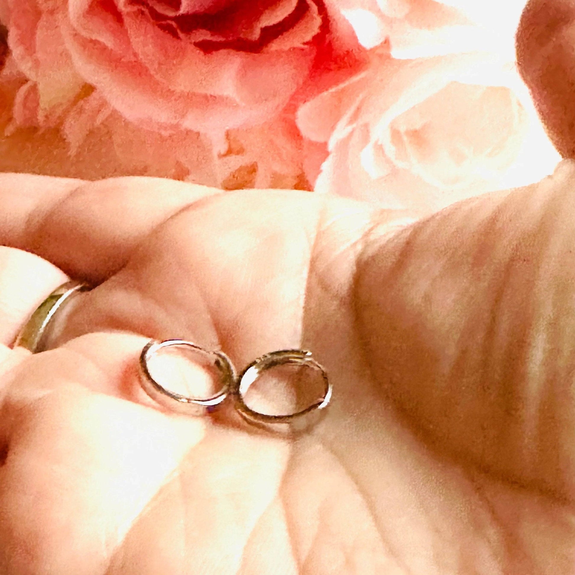Small silver huggie hoop earrings displayed in hand, showcasing their compact size and polished finish. Ideal for minimalist style.
