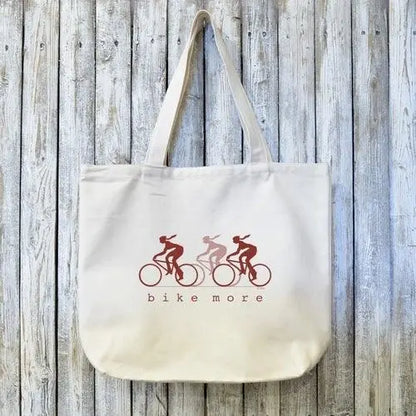 Cycling Gift Tote Bag with BIKE MORE design featuring three cyclists in red tones on organic cotton. Ideal for eco-conscious bike lovers.