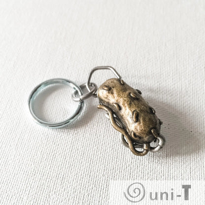 Bacterium Keychain - Bacteria Gift | Educational, Unique bronze-toned bacteria-shaped keychain with detailed surface texture and flagella.