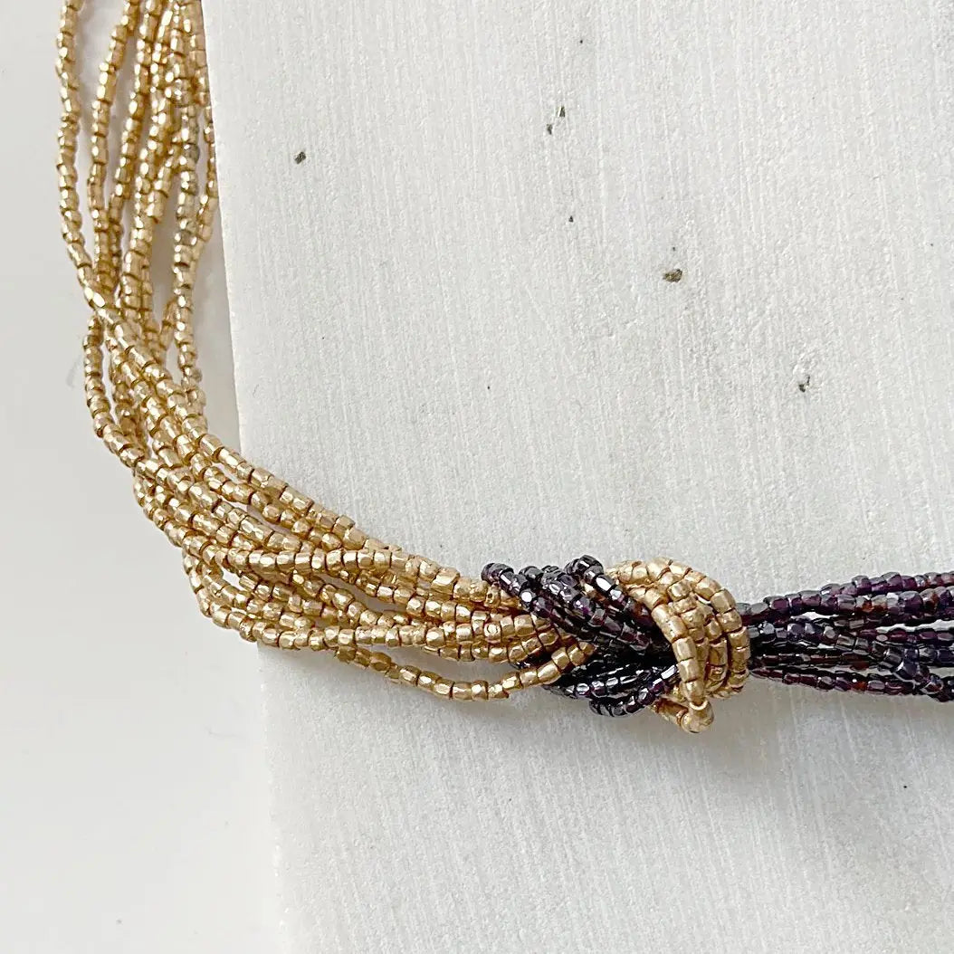 Beaded Two Tone Knot Necklace highlighting the contrast between golden and burgundy strands tied in a decorative knot. Ideal for Zoom calls or events.