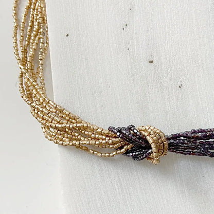 Beaded Two Tone Knot Necklace highlighting the contrast between golden and burgundy strands tied in a decorative knot. Ideal for Zoom calls or events.