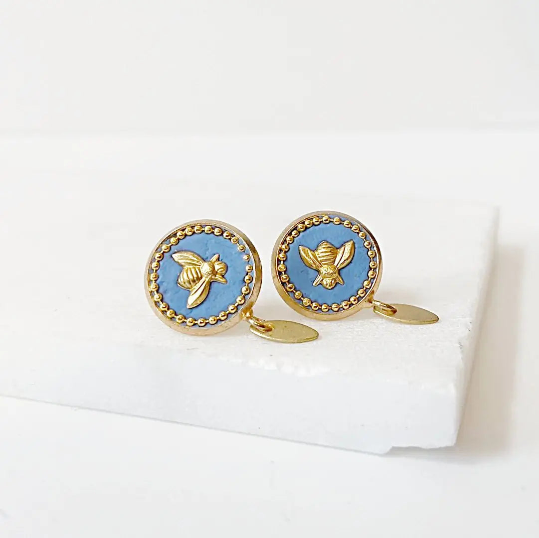 Bee stud earrings with brass posts and blue crystal background, featuring gold bee design and beaded trim, perfect for stylish accessorizing.