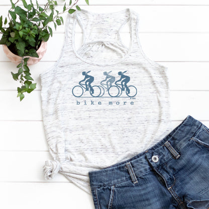 White speckled flowy tank top for women with blue 'bike more' cyclist print, styled with denim shorts for a casual eco-conscious look.