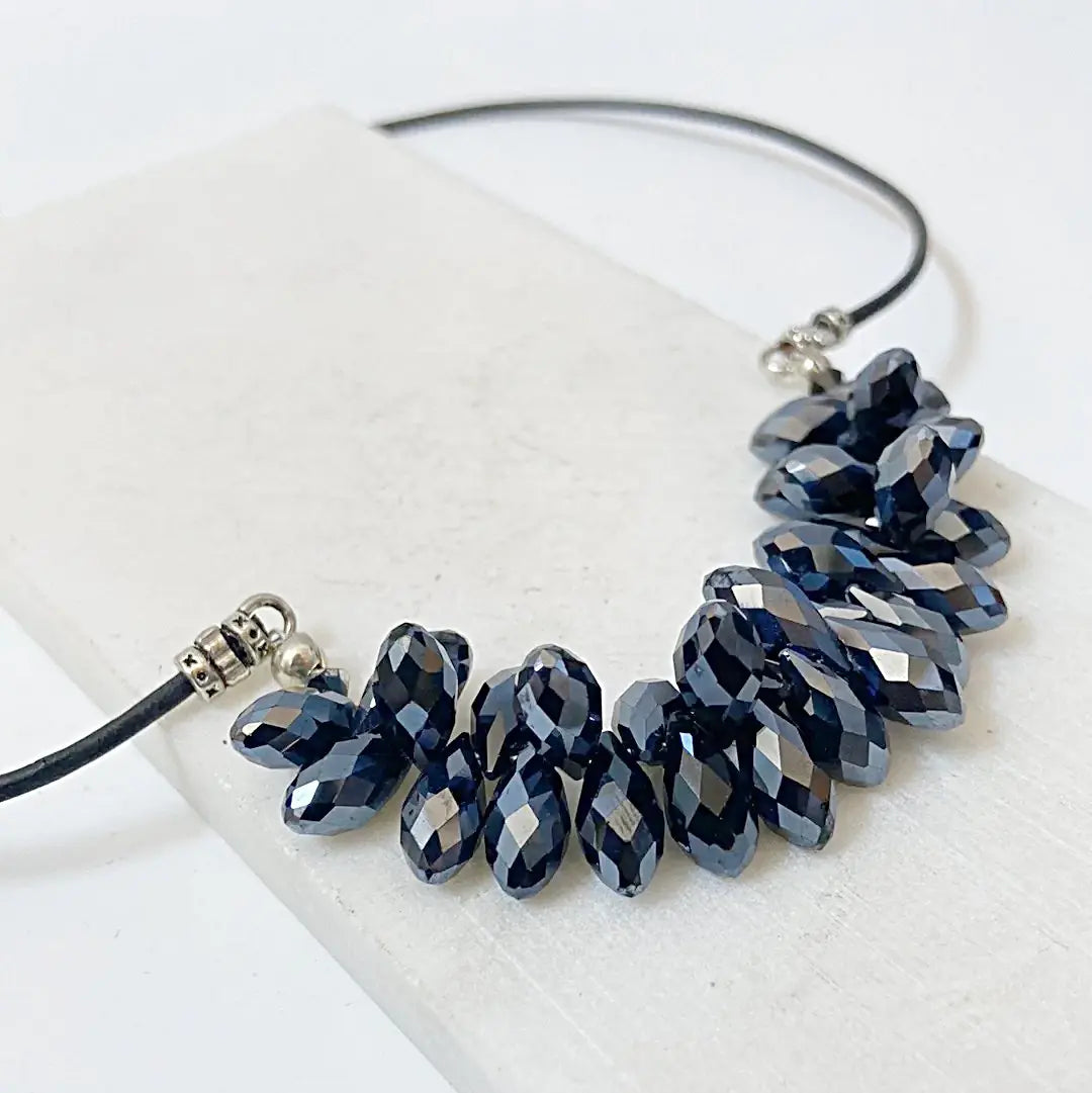 Angled view of the Black Crystal Necklace showing the sparkle of faceted black crystals on a leather cord, perfect for holiday wear.