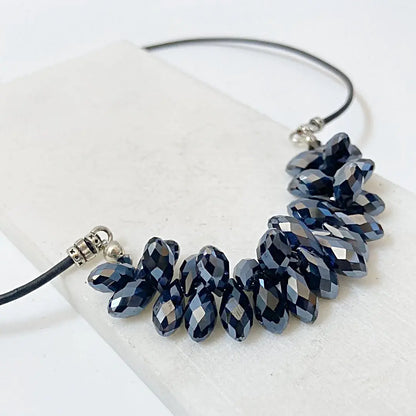 Angled view of the Black Crystal Necklace showing the sparkle of faceted black crystals on a leather cord, perfect for holiday wear.