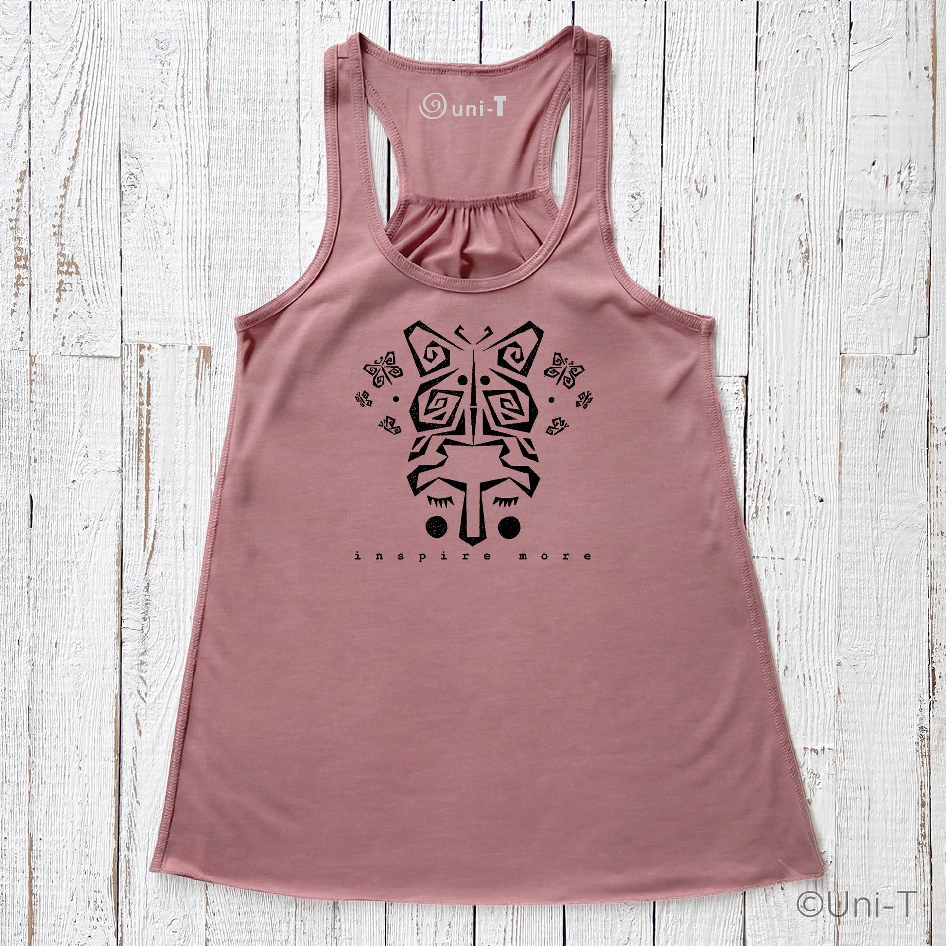 Rose pink "Inspire More" Tank Top with symbolic butterfly face graphic. Soft, USA-made top for women focused on personal growth and change.