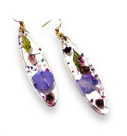 Pressed Flower Earrings featuring purple and green real flowers in resin. Gold hooks add elegance to this natural jewelry piece.