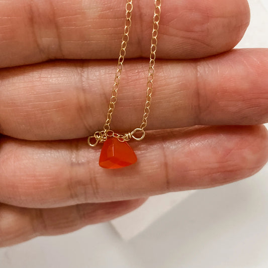 Close-up of Carnelian Gemstone Necklace from Uni-T showing hand-cut red gemstone pendant on delicate gold-filled chain held in hand.