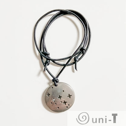 Cassiopeia Necklace - Science Jewelry featuring a round pewter pendant with star cutouts on a black cord, ideal for astronomy lovers.
