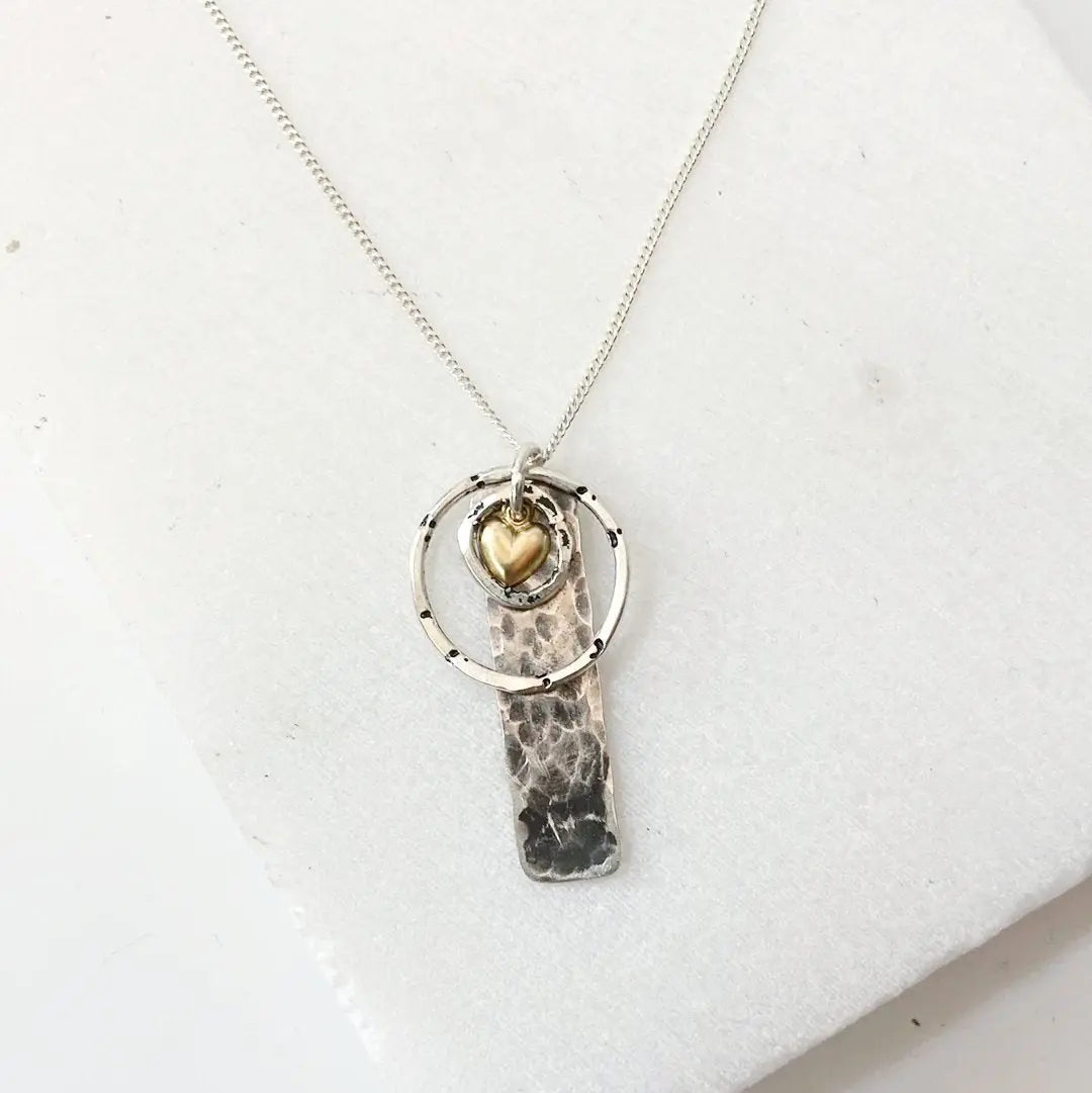 Sterling Circle Tag Necklace with hammered silver rectangle pendant, gold heart charm, and silver ring on 18-inch chain. Stylish gift for her.