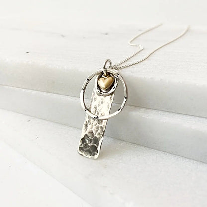 Silver Circle Tag Necklace with textured silver tag, gold heart accent, and sterling ring. Minimalist jewelry for everyday elegance.