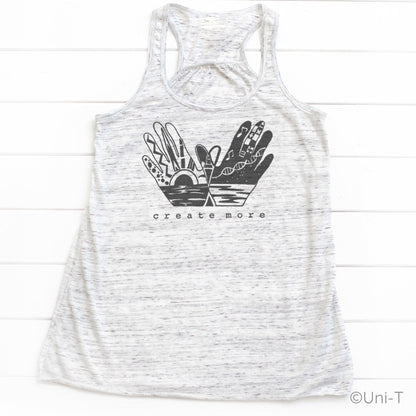 Heather white 'Create More' tank top featuring black hand art and sunrise design. Lightweight and stylish tank for creative women.