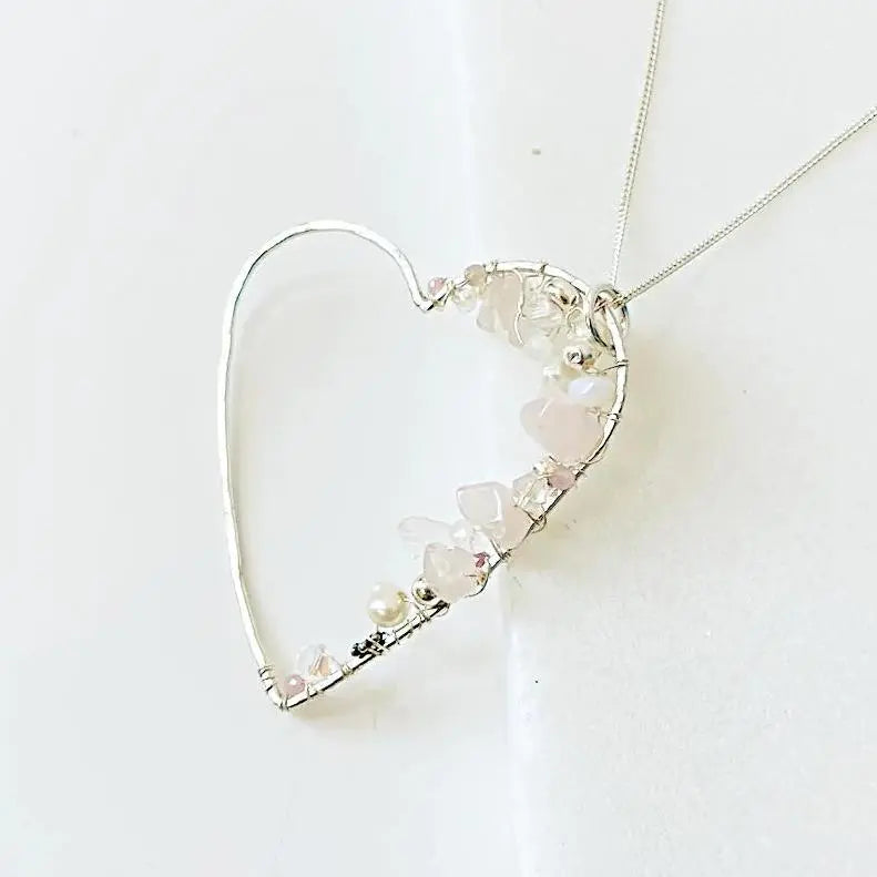 Close-up of Crystal Heart Necklace with pink gemstones and pearls on silver frame. Handcrafted sterling silver jewelry with 18” chain.