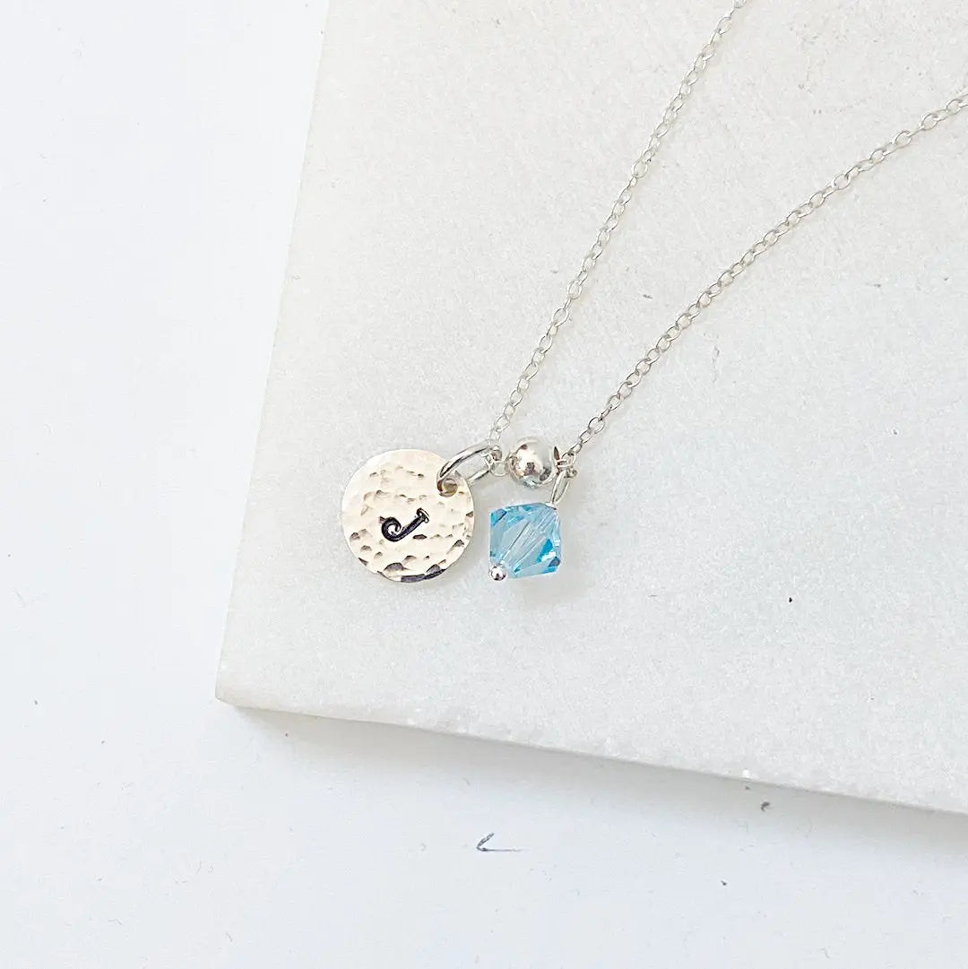 Custom Initial Necklace with silver chain, blue crystal accent, and engraved 'J' charm. Elegant personalized jewelry for everyday wear.