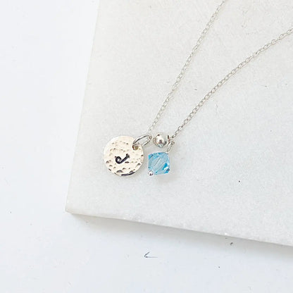 Custom Initial Necklace with silver chain, blue crystal accent, and engraved 'J' charm. Elegant personalized jewelry for everyday wear.