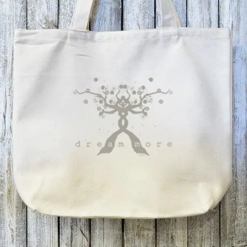 Close-up of Dream Chaser Tote Bag showing intricate tree and 'dream more' text, printed on sustainable organic canvas.