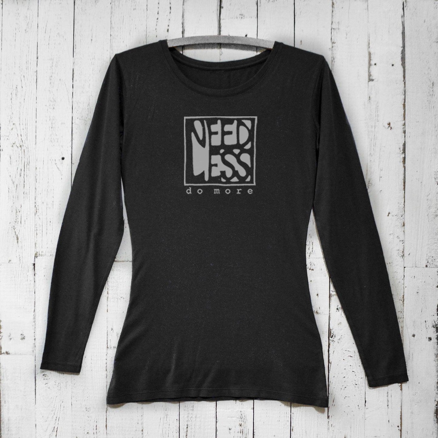Black women's bamboo and organic cotton long sleeve T-shirt featuring 'Need Less Do More' graphic. Sustainable minimalist gift by Uni-T.