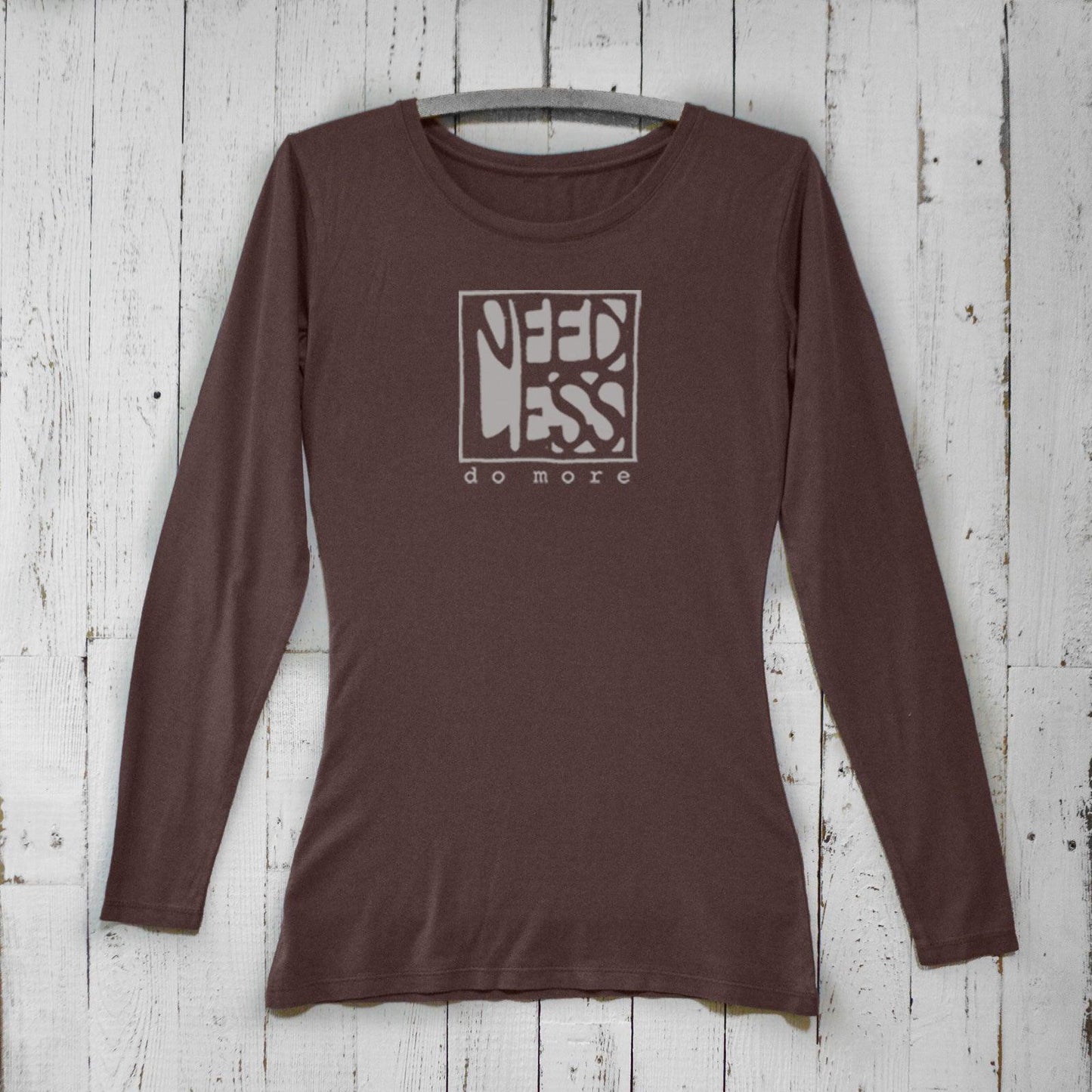 Dark brown women's long sleeve graphic tee made from bamboo and organic cotton. Features 'Need Less Do More' quote for intentional living.
