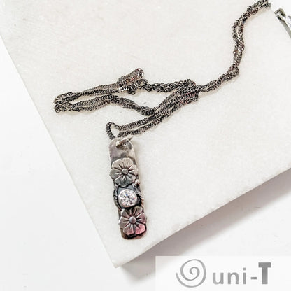 Cubic zirconia Flower Tag Necklace on oxidized silver rope chain, showcasing hand-soldered floral details and vintage-inspired design.