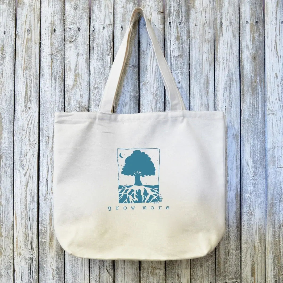 Organic canvas tote bag with 'Grow More' tree and roots artist design in blue ink. Eco-friendly and ideal for gardeners and sustainable living.