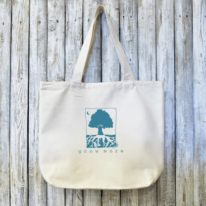 Organic canvas tote bag with 'Grow More' tree and roots artist design in blue ink. Eco-friendly and ideal for gardeners and sustainable living.