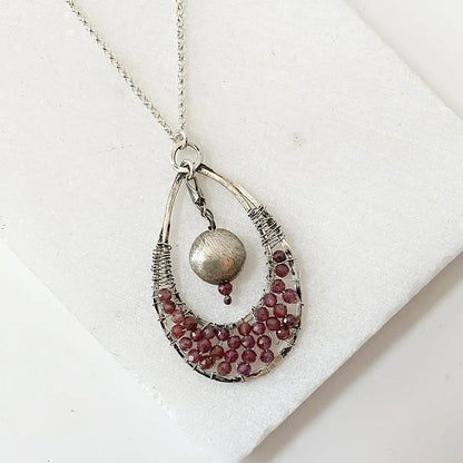 Artisan Garnet Necklace with teardrop pendant on 18" sterling silver chain, showcasing intricate wirework and clustered garnet stones.