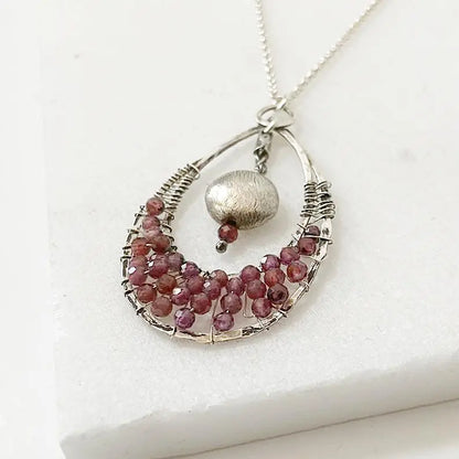 Close-up of Garnet Teardrop Pendant Necklace with deep red garnet beads and textured silver ball on sterling silver chain, perfect for elegant styling.