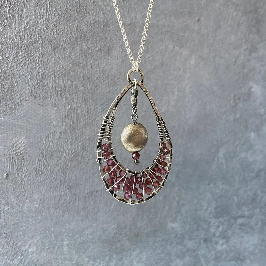 Front view of Garnet Teardrop Pendant Necklace with sterling silver chain, featuring a brushed silver bead and garnet accents in a teardrop frame.