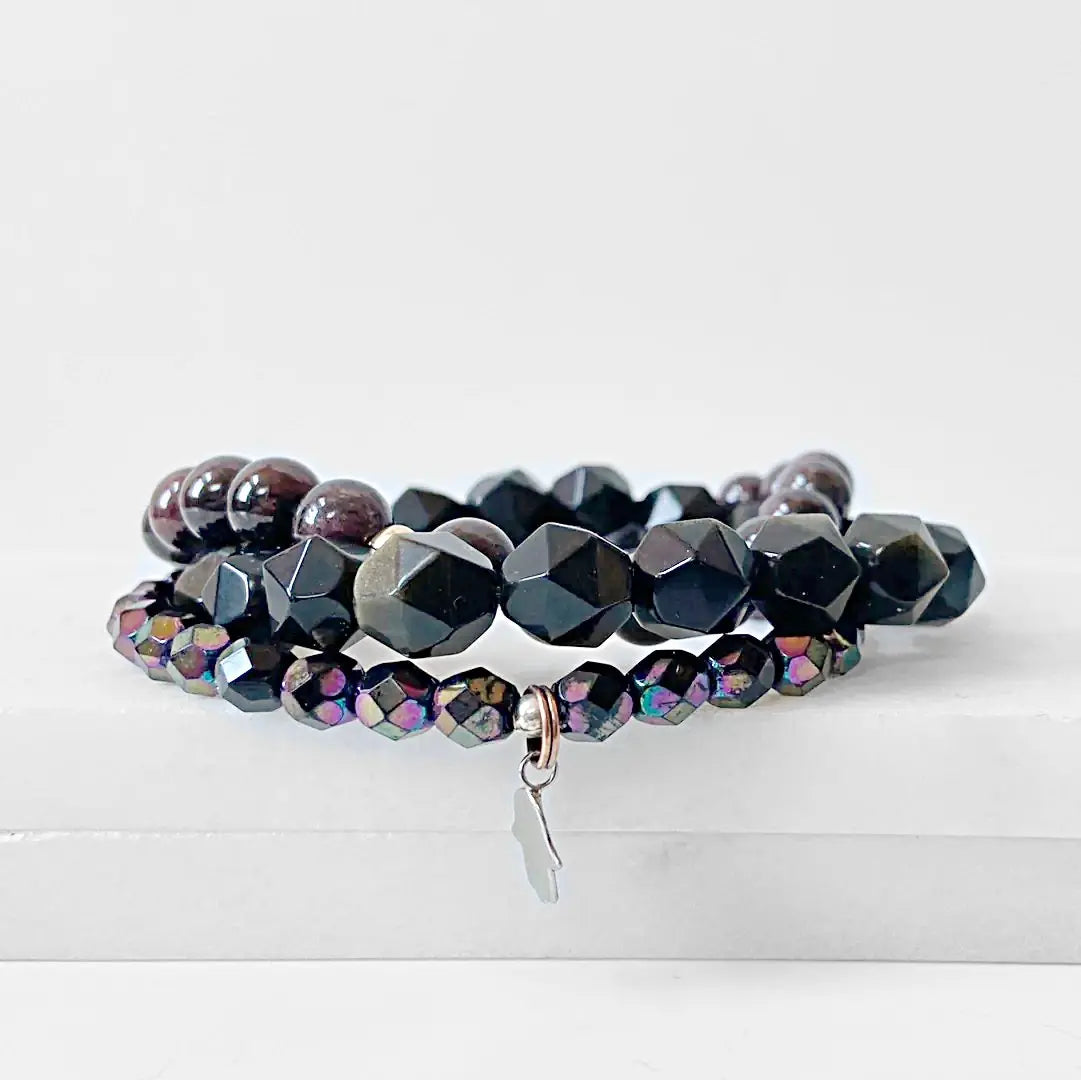 Stylish Garnet Black Obsidian Bracelet stack with metallic Czech glass beads and silver charm, ideal for versatile accessorizing.