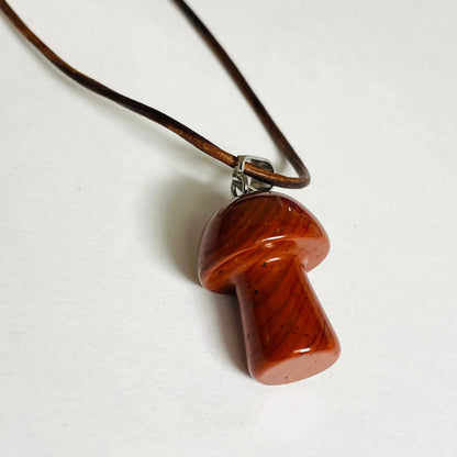 Close-up of Jasper Mushroom Necklace with a smooth carved pendant on a brown leather cord, highlighting its natural red-brown grain.
