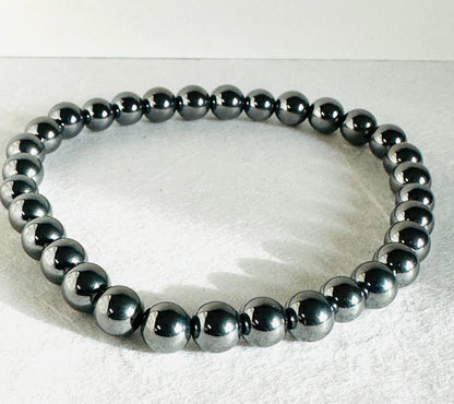 Polished hematite gemstone stretch bracelet with metallic shine, ideal for grounding energy and modern fashion.
