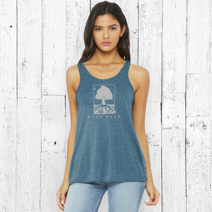 Model wearing "Grow More" flowy tank top in blue, eco-friendly women's clothing ideal for nature lovers and mindful living.