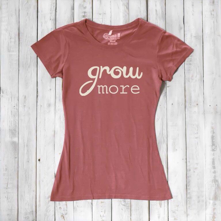 Terracotta red women's graphic tee with 'Grow More' quote in cream. Made from bamboo and organic cotton, ideal for eco-conscious gardeners.