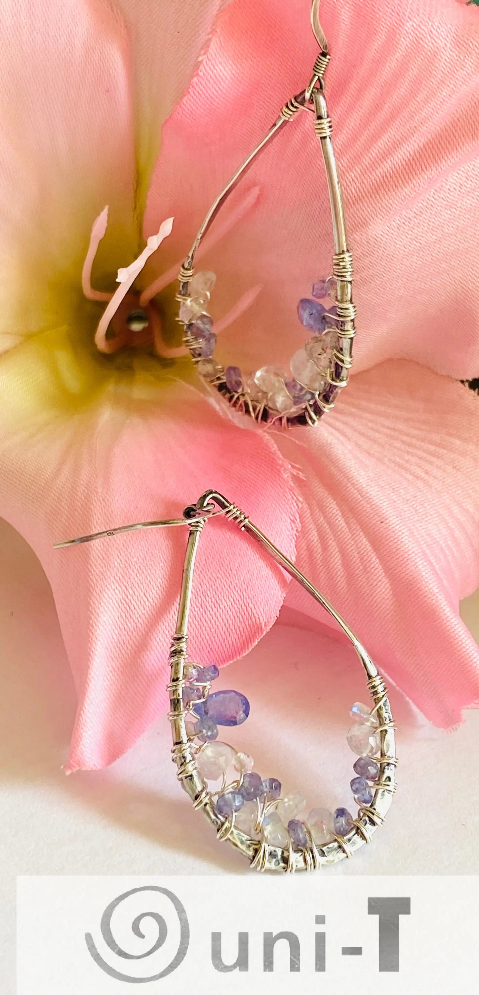 Teardrop Iolite and Moonstone Earrings with sterling silver wire wrap. Handmade gemstone earrings displayed with pink flower.