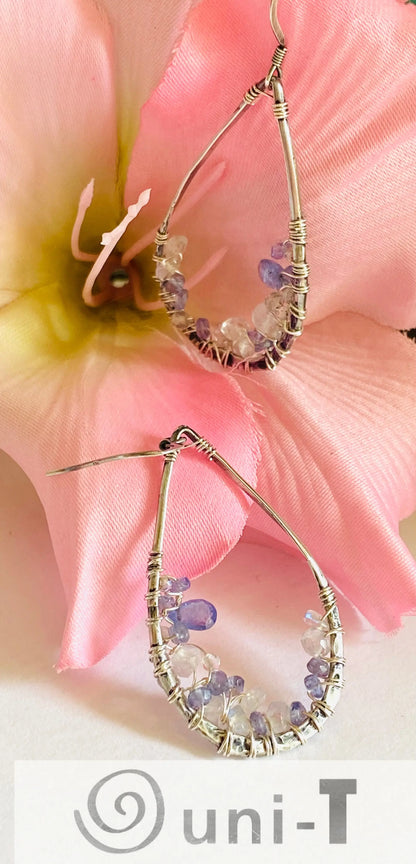 Teardrop Iolite and Moonstone Earrings with sterling silver wire wrap. Handmade gemstone earrings displayed with pink flower.