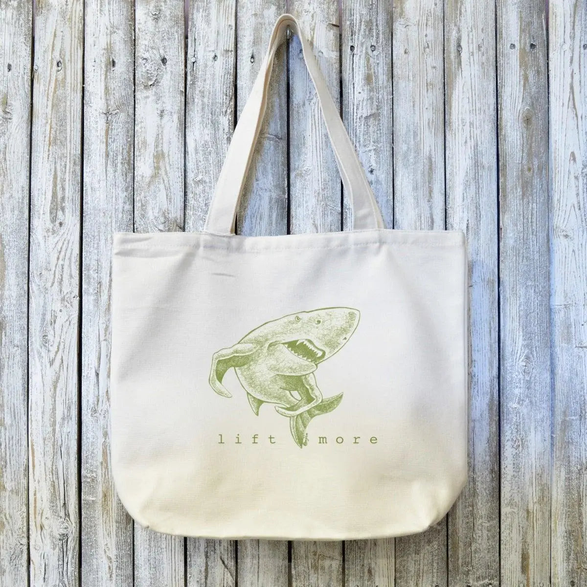 Fitness Tote Bag - Organic Canvas with shark illustration and 'lift more' text. Durable gym accessory for weightlifters, eco-friendly and artist-designed.
