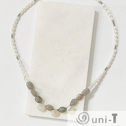 Labradorite and pearl necklace with adjustable length, displayed on a white stone slab to highlight gemstone details and silver clasp.