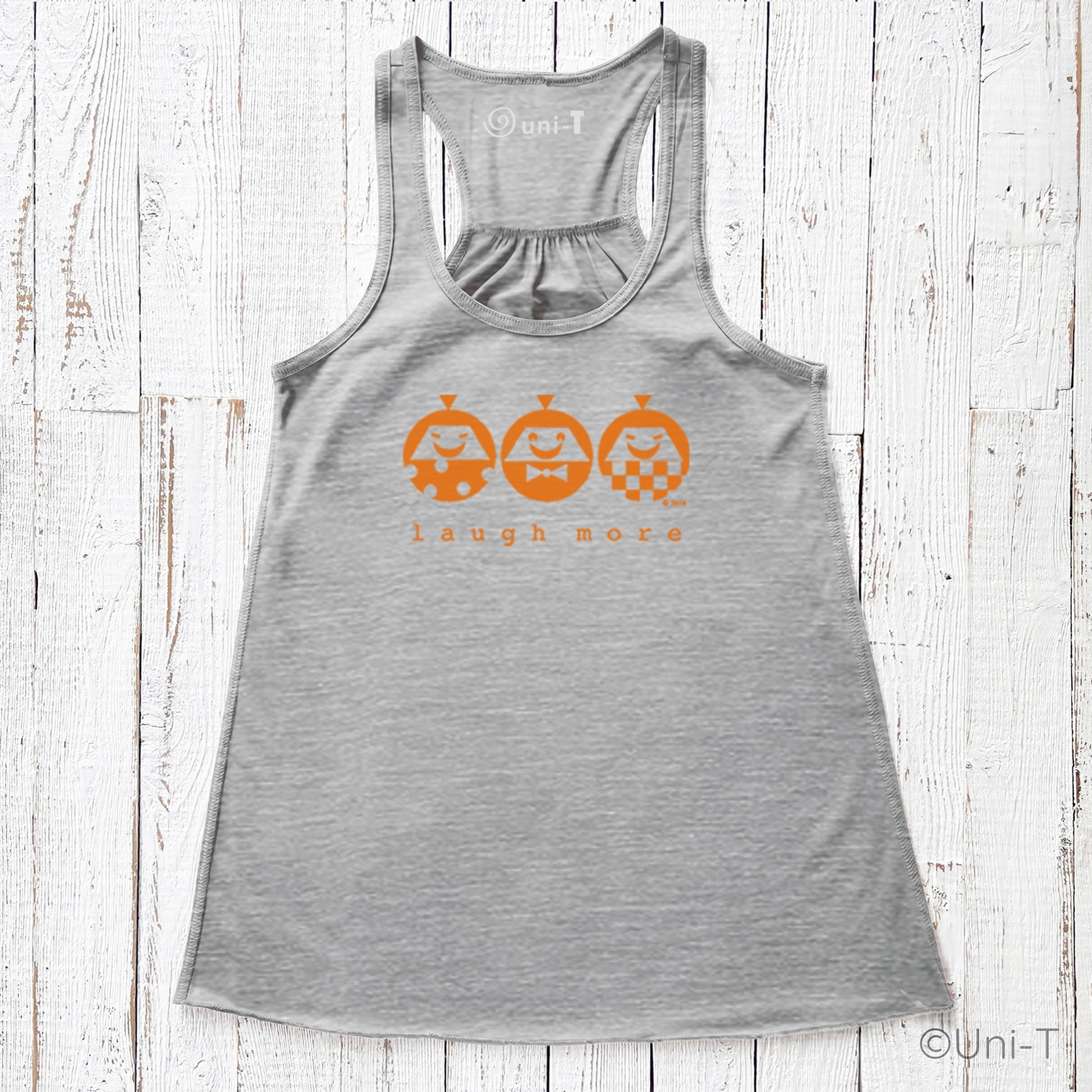 Heather gray women's flowy tank top with orange 'Laugh More' print. Comfortable and stylish for spreading positivity in everyday outfits.