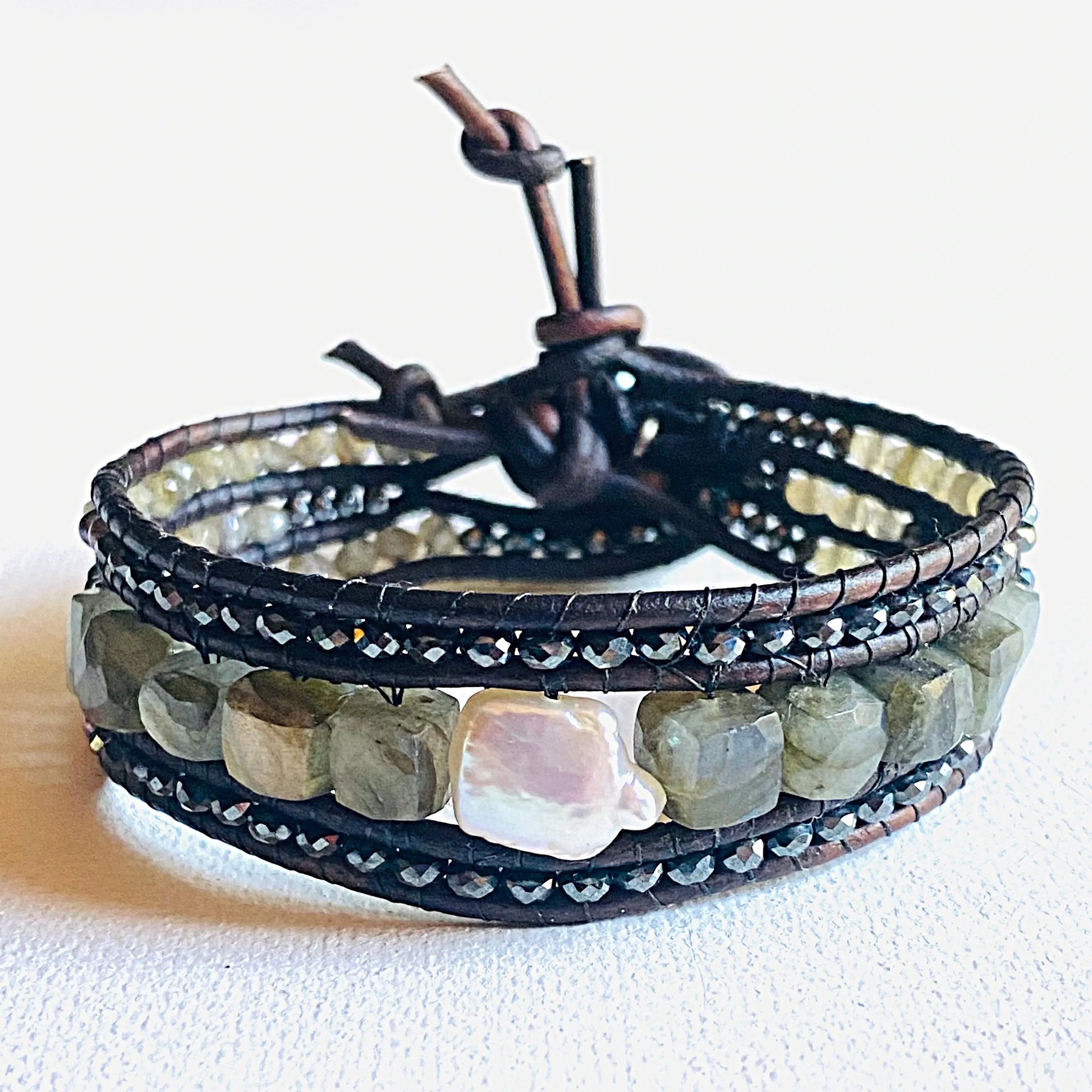 Leather gemstone bracelet with pearl and labradorite centerpiece, multi-strand design featuring hematite and crystal accents, 7.2” long.