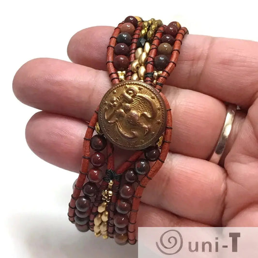 Close-up of gemstone cuff bracelet showing brass button closure and multi-colored gemstone beads on leather band.