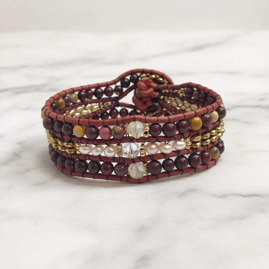 Back view of multi gemstone cuff bracelet with pearl, quartz, and leather detailing, secured by a floral loop closure.