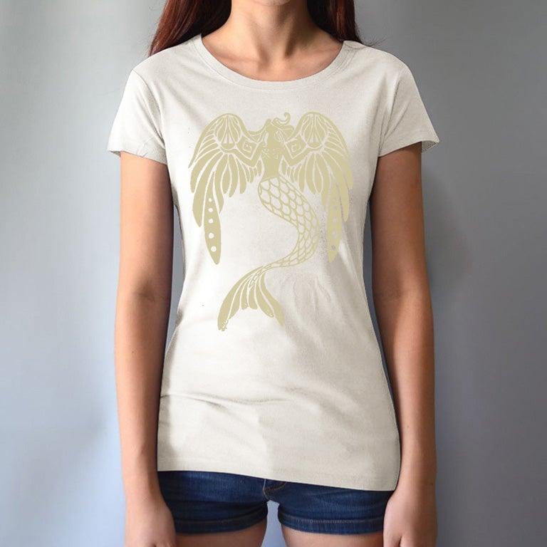 Cream Women's Mermaid T-Shirt in bamboo & organic cotton worn by model, featuring gold fantasy mermaid print. Soft and sustainable ocean-themed tee.