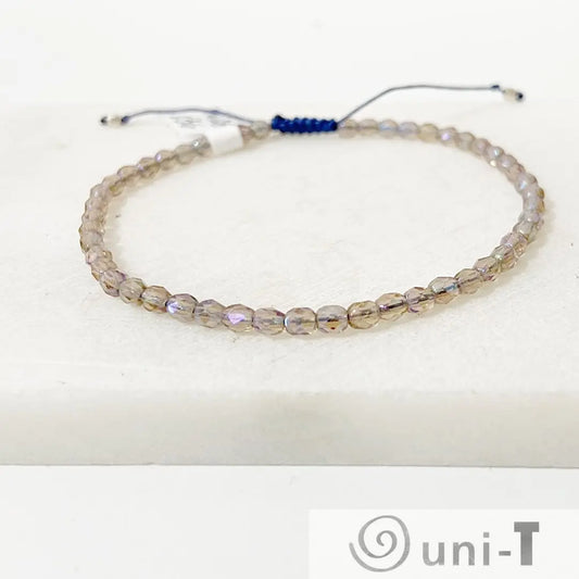 Micro glass adjustable bracelet featuring iridescent beads and a blue pull-tie closure, ideal for stacking and gifting.