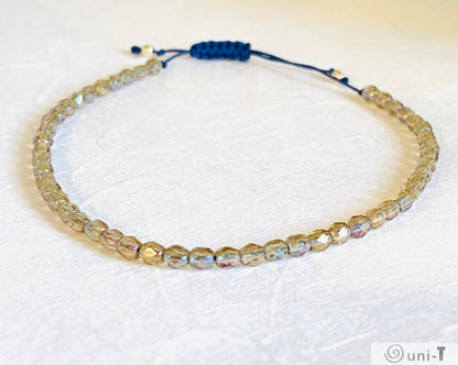 Stackable micro glass friendship bracelet with shimmering beads and adjustable navy thread, stylish and secure fit.